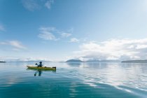 Man sea kayaking on sunny day inan inlet on the Alaska coastline. — Stock Photo