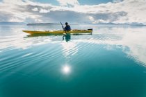 Человек плавает на каяке в солнечный день в заливе на побережье Аляски. — стоковое фото