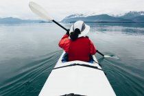 Жінка середніх літ веслує морем каяк у первозданній воді Muir Inlet, Glacier Bay National Park and Preserve, Alaska — стокове фото