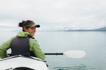 Happy female woman sea kayaking pristine waters of Muir Inlet in Glacier Bay National Park and Preserve, Alaska — Stock Photo