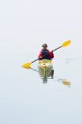 Female sea kayaker paddling pristine waters of Muir Inlet, overcast sky in distance, Glacier Bay National Park, Alaska — Stock Photo