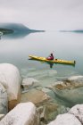 Kajakfahrerin paddelt unberührtes Wasser des Muir Inlet, bewölkter Himmel in der Ferne, Glacier Bay National Park, Alaska — Stockfoto