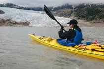 Un kayakiste de mer s'approche d'un terminus glaciaire, où la glace rencontre la mer. — Photo de stock