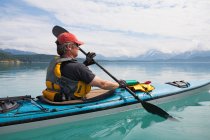 Man sea kayaking calm waters of an inlet in a national park. — Stock Photo