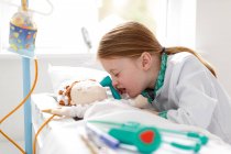 Giovane ragazza vestita da medico che finge di trattare il paziente nel letto d'ospedale make-bleieve — Foto stock