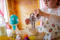 Молодая девушка в Венди Хаус с помощью игрушечного венчика притворяется, что готовит на кухне — стоковое фото