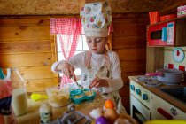 Jeune fille dans wendy maison prétendant cuisiner dans la cuisine — Photo de stock
