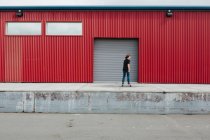 Teenagerjunge skateboardet vor Verladezone einer Industriehalle — Stockfoto