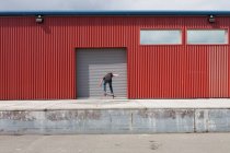 Хлопчик-підліток скейтбординг перед промисловою зоною завантаження складів — стокове фото