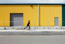 Teenage boy skateboarding in front of industrial warehouse loading zone — Stock Photo