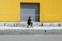 Хлопчик-підліток скейтбординг перед промисловою зоною завантаження складів — стокове фото