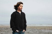 Portrait of moody teenage boy on beach — Stock Photo