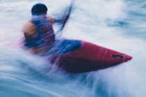 Lange Belichtung männlicher Wildwasser-Kajakfahrer beim Paddeln und Surfen großer Stromschnellen auf einem schnell fließenden Fluss. — Stockfoto