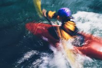 Larga exposición de kayakistas de aguas bravas hembras remando rápidos y surf en un río que fluye rápido. - foto de stock