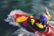 Long exposure of female whitewater kayaker paddling rapids and surf on a fast flowing river. — Stock Photo