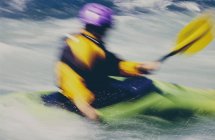 Long exposure of female whitewater kayaker paddling rapids and surf on a fast flowing river. — Stock Photo
