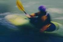 Longue exposition de kayakistes d'eau vive femelles pagayant sur des rapides et surfant sur une rivière à écoulement rapide. — Photo de stock