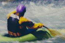 Longa exposição de mulheres caiaque caiaque remando corredeiras e surf em um rio que flui rápido. — Fotografia de Stock