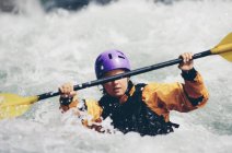 Weibliche Wildwasser-Kajakfahrerin paddelt Stromschnellen und surft auf einem schnell fließenden Fluss. — Stockfoto