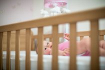 Baby liegt auf dem Rücken im Kinderbett und blickt in die Kamera — Stockfoto