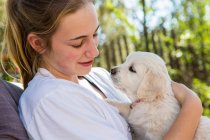 Teenage girl holding golden retriever puppy — Stock Photo