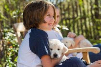 6 year old boy holding an English golden retriever puppy — Stock Photo