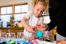 3-jähriges Mädchen färbt Ostereier zu Hause mit ihrer Mutter — Stockfoto