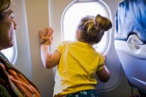 Junges Mädchen blickt aus Flugzeugfenster — Stockfoto