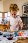 Трехлетняя девочка раскрашивает яйца в домашних условиях — стоковое фото
