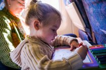Young girl drawing on airplane, side view — Stock Photo