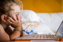 3-jähriges Mädchen schaut Laptop im Hotelzimmer an — Stockfoto