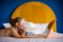 3-річна дівчина дивиться на ноутбук у готельному номері — стокове фото