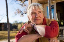 Mature woman at home on her property in a rural setting resting her chin on her hands — Stock Photo