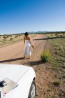 Mulher nativa americana em vestido de sol dirigindo um carro esporte conversível branco na sujeira do deserto — Fotografia de Stock