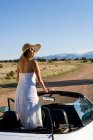 Коренная американка в солнечном платье водит белый кабриолет на грунтовой дороге пустыни — стоковое фото