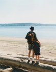 Father and son standing driftwood log and taking in view of Puget Sound — Stock Photo