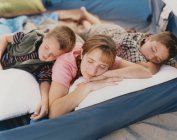 Mother and her two young sons resting in camping tent on beach — Stock Photo
