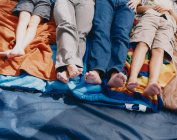 Vierköpfige Familie liegt auf Schlafsäcken im Zelt, Taille runter — Stockfoto