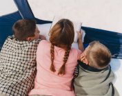 Мать читает своим сыновьям в палатке для кемпинга — стоковое фото