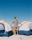 Adolescent boy standing by camping tents on beach — Stock Photo