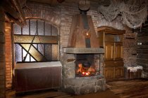 A hotel with old fashioned retro styled rooms, and rustic objects, open lit fire with large stonework chimney and wooden floor — Stock Photo