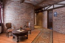 Ein Hotel mit altmodischen Zimmern im Retro-Stil und rustikalen Objekten, exponierter Steinmauer und Tisch und Stühlen — Stockfoto