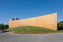 Edifícios universitários modernos, vigas de madeira projetadas a partir de uma parede de revestimento de madeira curva, em uma superfície de solo curvo — Fotografia de Stock