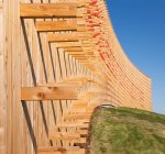 Moderni edifici universitari, travi in legno sporgenti da una parete di rivestimento in legno curvato, su una superficie ricurva — Foto stock