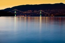 Illuminated Bridge Across a Bay and Dark Hills at Dusk — Stock Photo