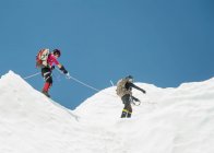 Dos escaladores en la nieve en una montaña, atados juntos. - foto de stock