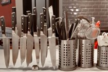 Кухонная столешница, ряды ножей на магнитной ленте и посуда в горшках. — стоковое фото