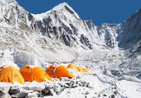 Group of orange tents at a climbers base camp in the Himalayas region. — Stock Photo