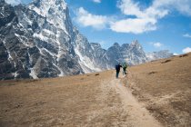 Dos escaladores en un sendero frente a las empinadas montañas. - foto de stock