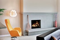 Living room in a modern house, with a fireplace and mantlepiece and hearth, and a modern yellow chair. — Stock Photo